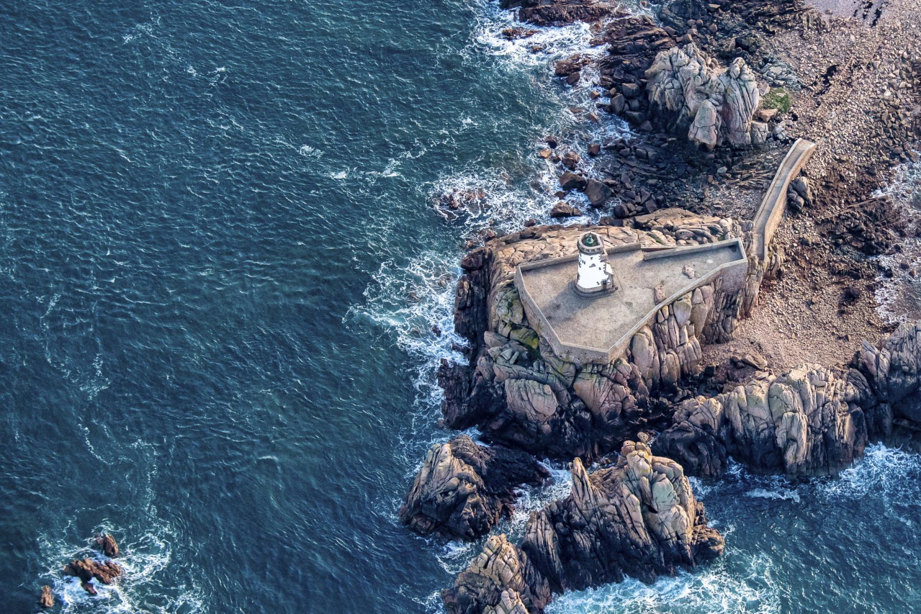 Photographie Le Phare du Paon se dresse fièrement face à la Manche. Cette prise de vue aérienne souligne le contraste entre la pierre brute et la force de l'océan.
