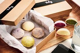 Assortiment de mochis glacés colorés dans une boîte en carton sur un plateau en bois, lumière naturelle