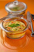 Cassolette de surimi gratinée dans un ramequin en verre avec feuille de basilic sur un fond orange et couverts en métal.