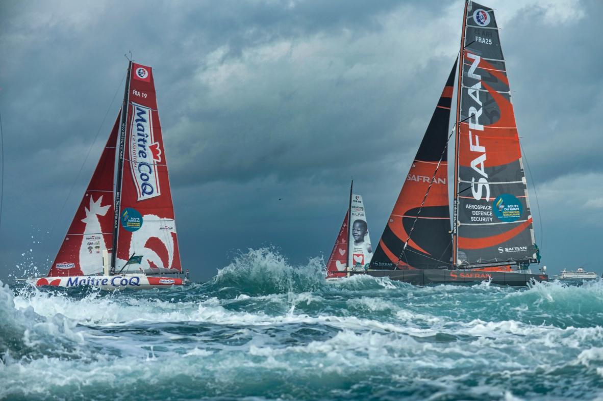 Voiliers de course Maître Coq et Safran franchissant les vagues écumantes sous un ciel chargé à Saint-Malo