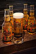Verre de bière blonde avec mousse épaisse devant quatre bouteilles de biere sur un comptoir sombre, éclairage chaleureu