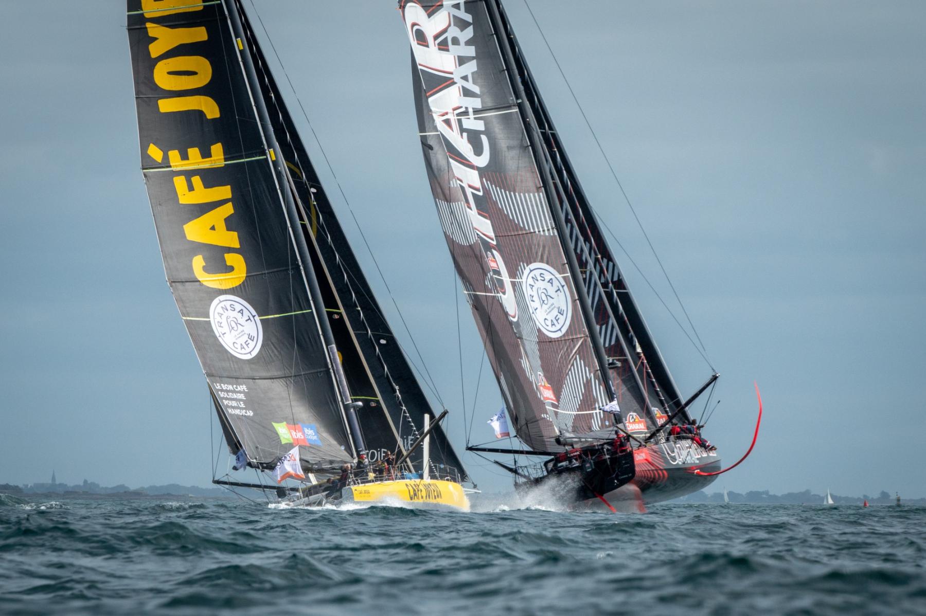 Voiliers IMOCA Café Joyeux et Charal en pleine régate à Lorient. Charal décolle sur ses foils.