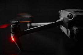 Gros plan d’un drone professionnel avec voyant rouge allumé sur un fond noir, illustrant la technologie de prise de vue.